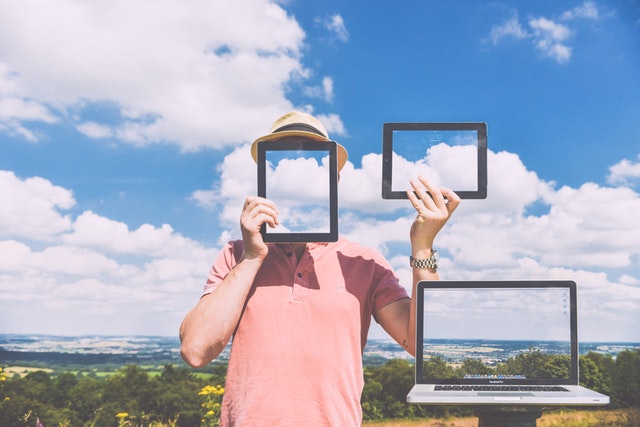 man holding three screens outdoors